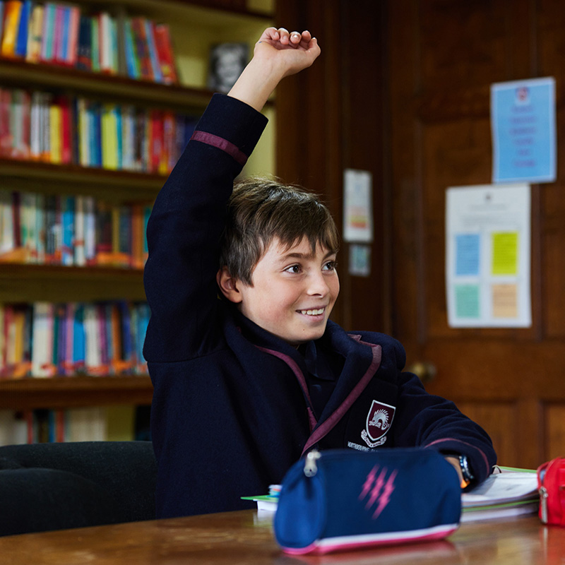 photo of a student putting his hand up in class